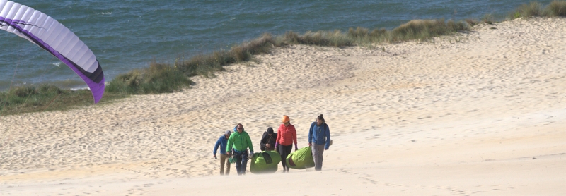 5 personnes transportant une voile de parapente