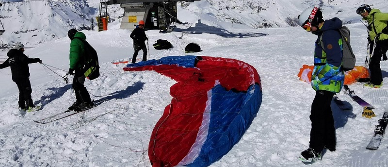 Cinq personnes sur la neige en attente de décoller en parapente